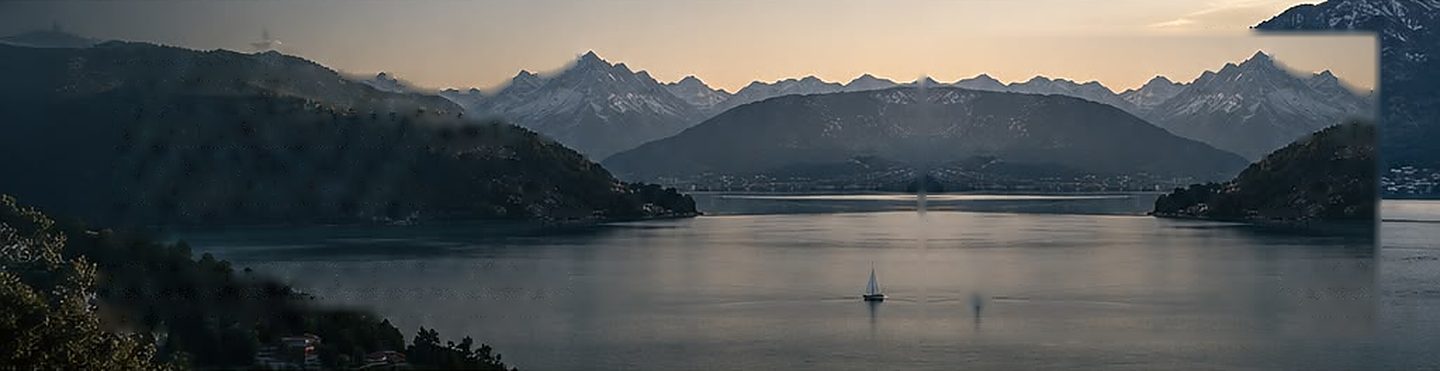 Bergsee in der Abenddämmerung mit Segelboot